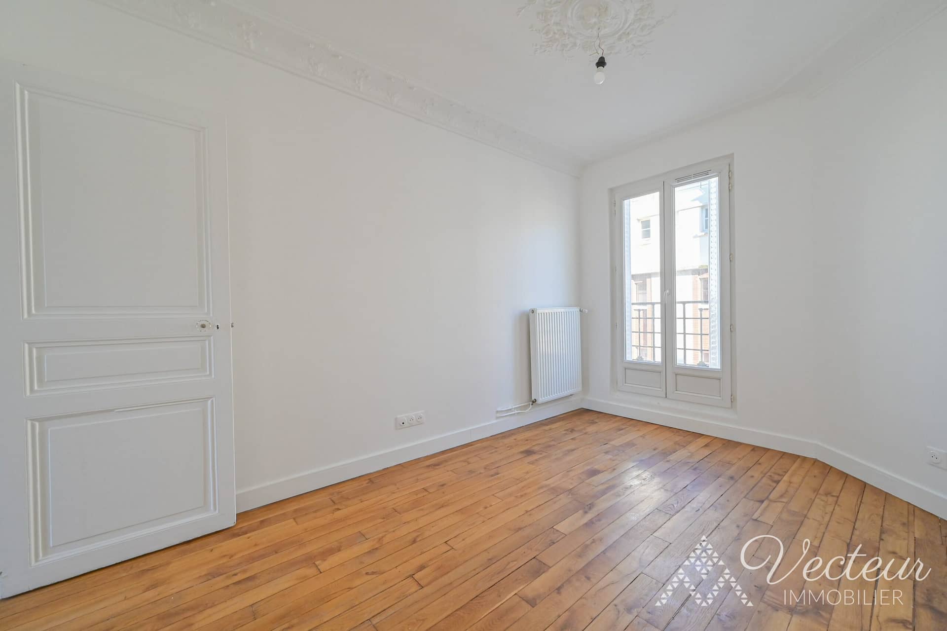 Chambre avec parquet et fenêtre d'un appartement à Paris 15