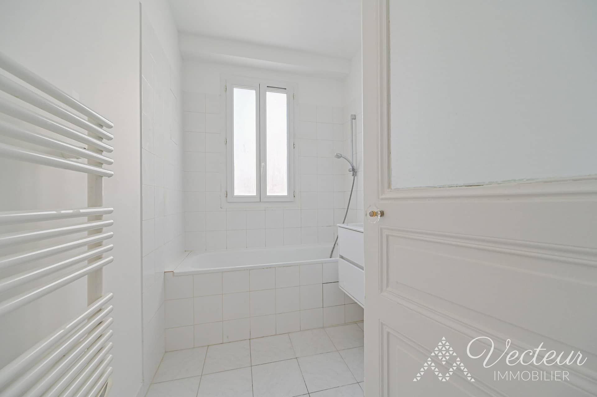 Salle de bains avec baignoire et fenêtre d'un appartement à Paris 15